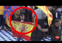 Un hombre sube al escenario de la marcha independentista con una bandera de España y el lema ‘Viva el Rey’