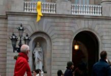 Un grupo de personas retira el lazo amarillo del Ayuntamiento de Barcelona