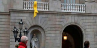 Un grupo de personas retira el lazo amarillo del Ayuntamiento de Barcelona