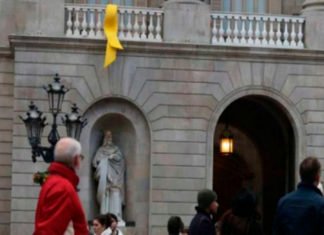 Un grupo de personas retira el lazo amarillo del Ayuntamiento de Barcelona