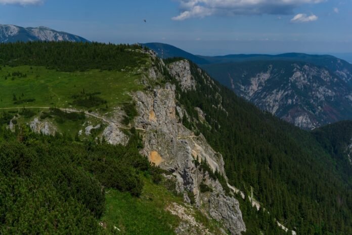 a rocky mountain with trees and a river running through it