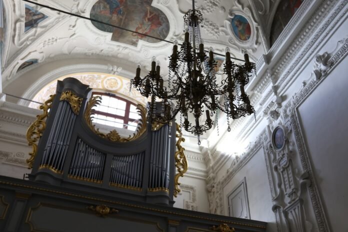 Ornate pipe organ and chandelier in a grand hall.