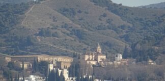 Granada destaca en los reconocimientos del Día de Andalucía con tres distinguidos galardonados A cityscape with buildings and mountains in the background.