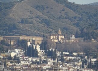 Granada destaca en los reconocimientos del Día de Andalucía con tres distinguidos galardonados A cityscape with buildings and mountains in the background.