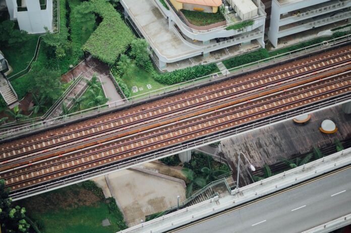 aerial photography of train rails between bridge and building