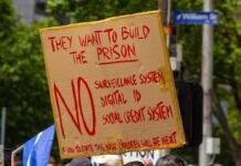 La Dependencia de las Subvenciones: ¿Frena o Impulsa el Futuro del Vehículo Eléctrico? a person holding a sign that says they want to build the prison