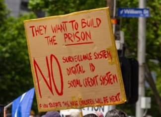 La Dependencia de las Subvenciones: ¿Frena o Impulsa el Futuro del Vehículo Eléctrico? a person holding a sign that says they want to build the prison
