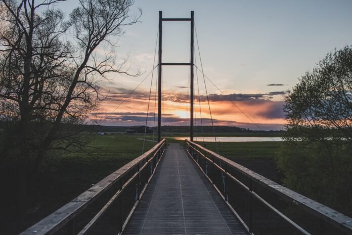 image_1772049627430 a wooden bridge with a sunset in the background