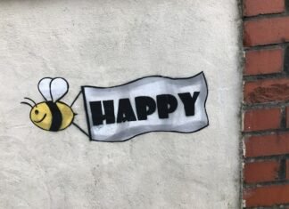 La Búsqueda de la Felicidad Auténtica: Más Allá del Éxito Material y las Experiencias Superficiales a sign that says happy with a bee on it