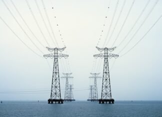 La Volatilidad Energética Global: Cuando los Mercados Anticipan Escenarios Extremos A couple of power poles sitting in the middle of a body of water