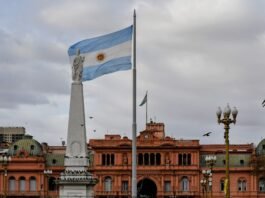 El turismo uruguayo en transformación: desafíos y oportunidades tras la temporada estival Argentinian flag waving near a prominent building.