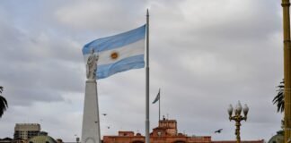 El turismo uruguayo en transformación: desafíos y oportunidades tras la temporada estival Argentinian flag waving near a prominent building.