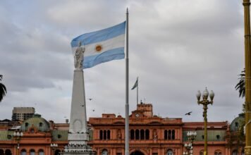 El turismo uruguayo en transformación: desafíos y oportunidades tras la temporada estival Argentinian flag waving near a prominent building.