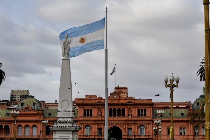 image_1773464426659 Argentinian flag waving near a prominent building.