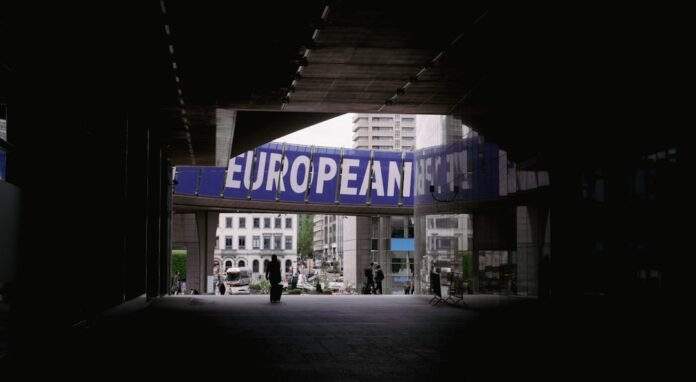 image_1774058432530 a person walking under a bridge with a european sign above it