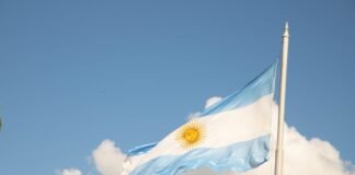 La ciencia forense argentina que trasciende fronteras: cuatro décadas devolviendo identidad a las víctimas a flag flying in the wind with a clock tower in the background