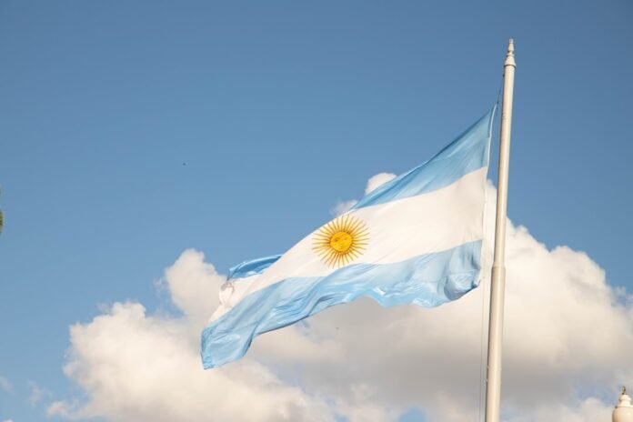 a flag flying in the wind with a clock tower in the background