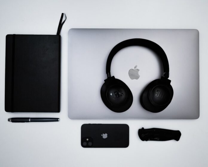 an apple laptop with headphones and a notebook