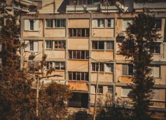 La crisis de la vivienda protegida en España: cuando el mercado privado no basta Apartment building facade framed by trees.