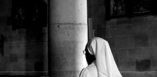 El papel de la mujer en la Iglesia Católica: entre tradición y modernidad en el siglo XXI grayscale photography of woman wearing veil sitting on bench