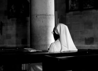 El papel de la mujer en la Iglesia Católica: entre tradición y modernidad en el siglo XXI grayscale photography of woman wearing veil sitting on bench
