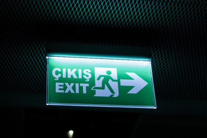 image_1775426431290 a green exit sign hanging from the side of a wall
