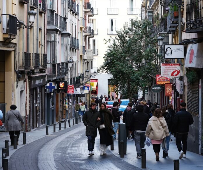 a group of people walking down a street next to tall buildings