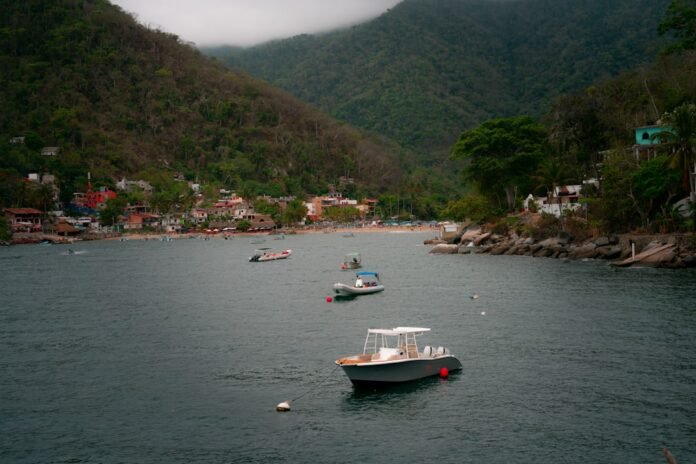image_1775847631912 Boats float in a bay with a town and mountains.