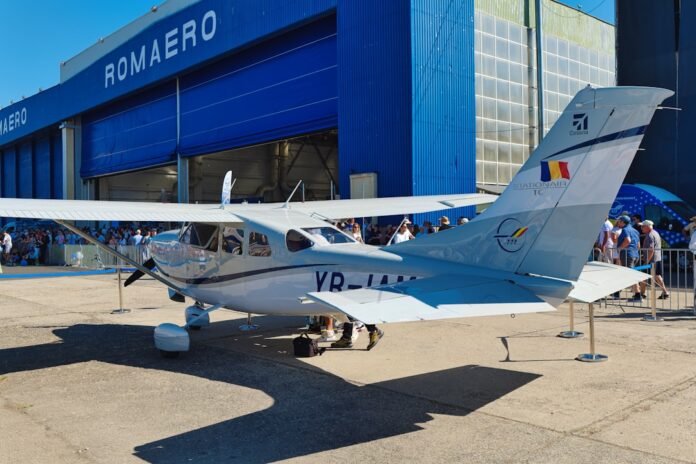 Small airplane parked outside a blue hangar