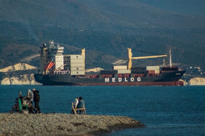 A group of people sitting on a rock next to a body of water