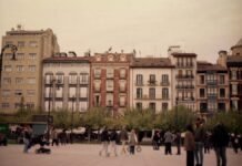 Huelga en gasolineras españolas amenaza con complicar los desplazamientos del puente de mayo People walking in a plaza with historic buildings