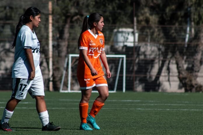 Two female soccer players are on a field.