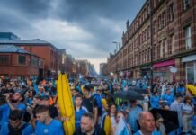 Manchester City recupera el liderato de la Premier League en la recta final de la temporada a large group of people walking down a street