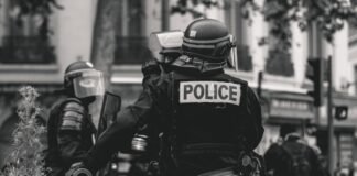 Controversia por agresión policial a manifestante en Valencia: cuando la fuerza pública traspasa los límites grayscale photo of Police standing and leaning on wall