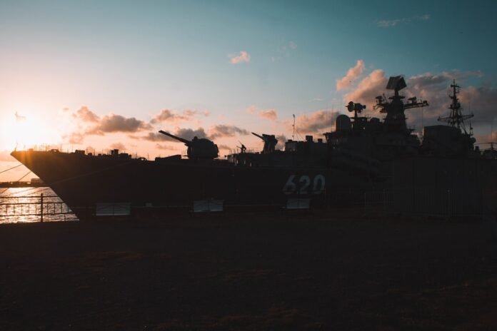 Silhouette of a warship at sunset with dramatic clouds
