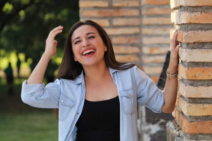 image_1781301627274 A young woman laughing with her hands in her hair