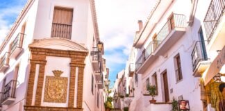Descubre los secretos de los pueblos costeros andaluces: refugios perfectos para el verano español a building with a clock on the side of it