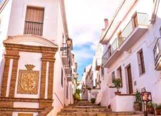 Descubre los secretos de los pueblos costeros andaluces: refugios perfectos para el verano español a building with a clock on the side of it