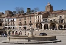 Extremadura experimenta un adelanto del calor veraniego con temperaturas cercanas a los 40 grados Old buildings surround a fountain in a sunny plaza.