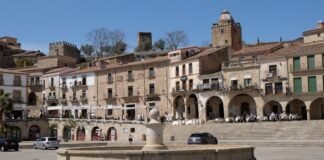 Extremadura experimenta un adelanto del calor veraniego con temperaturas cercanas a los 40 grados Old buildings surround a fountain in a sunny plaza.