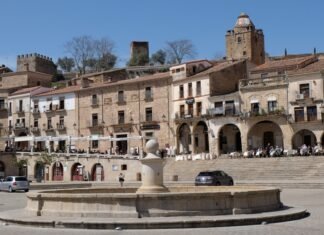Extremadura experimenta un adelanto del calor veraniego con temperaturas cercanas a los 40 grados Old buildings surround a fountain in a sunny plaza.