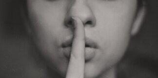 Ansiedad en silencio: cuando la sonrisa se convierte en la máscara más pesada grayscale photo of woman doing silent hand sign