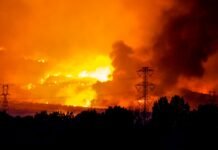 Incendios Simultáneos en Cataluña: El Gran Desafío Logístico que Pone a Prueba los Límites de la Protección Civil A massive wildfire rages under an orange, smoke-filled sky.