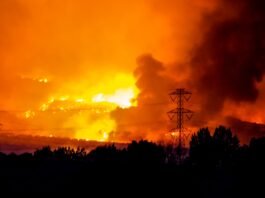 Incendios Simultáneos en Cataluña: El Gran Desafío Logístico que Pone a Prueba los Límites de la Protección Civil A massive wildfire rages under an orange, smoke-filled sky.