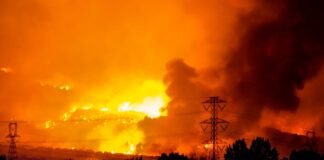 Incendios Simultáneos en Cataluña: El Gran Desafío Logístico que Pone a Prueba los Límites de la Protección Civil A massive wildfire rages under an orange, smoke-filled sky.