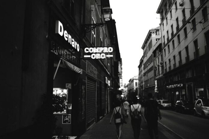 People walk down a street with shops and buildings.