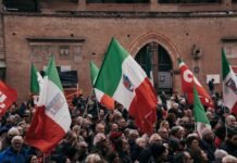 Italia vs España: La batalla por las fronteras de Schengen que sacude los cimientos de Europa A large group of people holding flags in front of a building