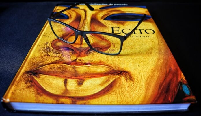 image_1786572037096 Glasses resting on a book with a face design.