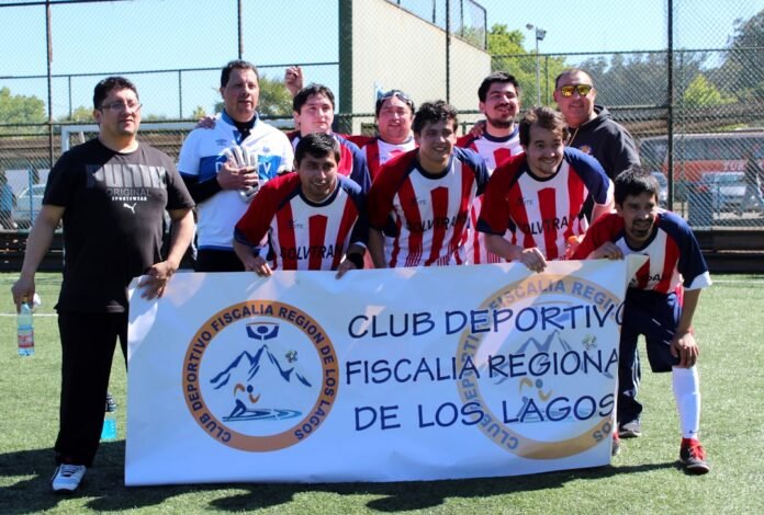 A group of men in soccer uniforms holding a banner on a sports field.