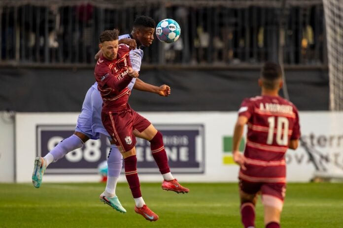 Two soccer players jump to head the ball
